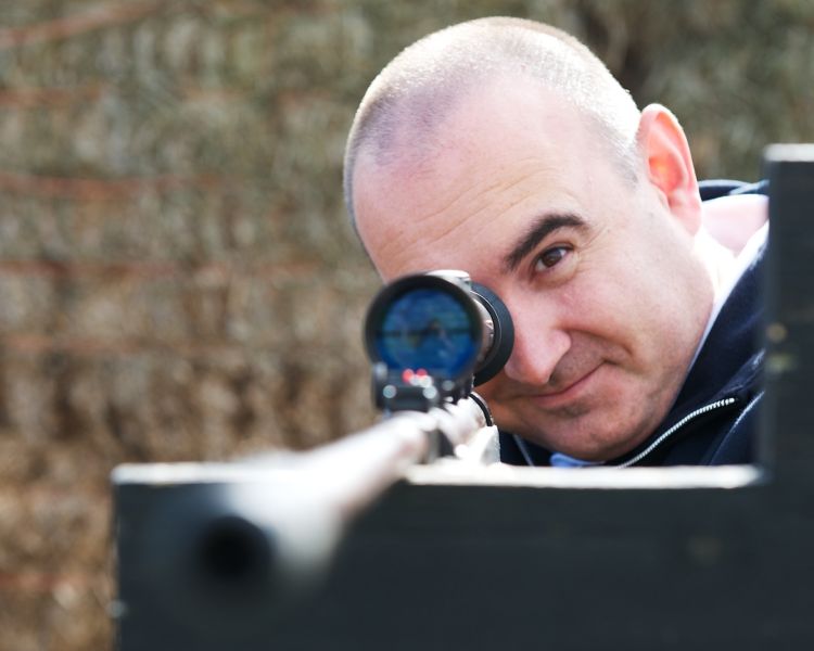 man aiming an air rifle while on a spy camp experience day for adults