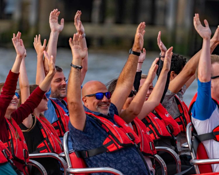 happy passengers with their arms in the air on a thames rockets ultimate speedboat experience on the thames in london