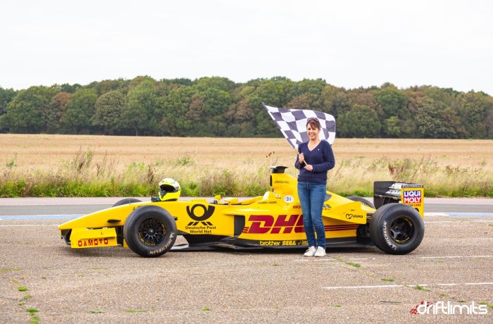 woman holding chequered flag next to f1 jordan car on a f1 car photoshoot and passenger lap experience