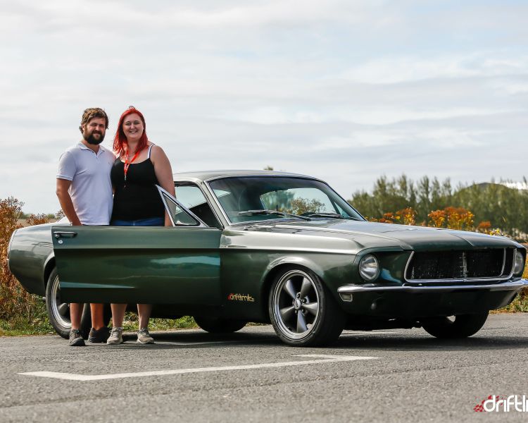 couple standing next to a vintage car on a car photoshoot and passenger lap experience