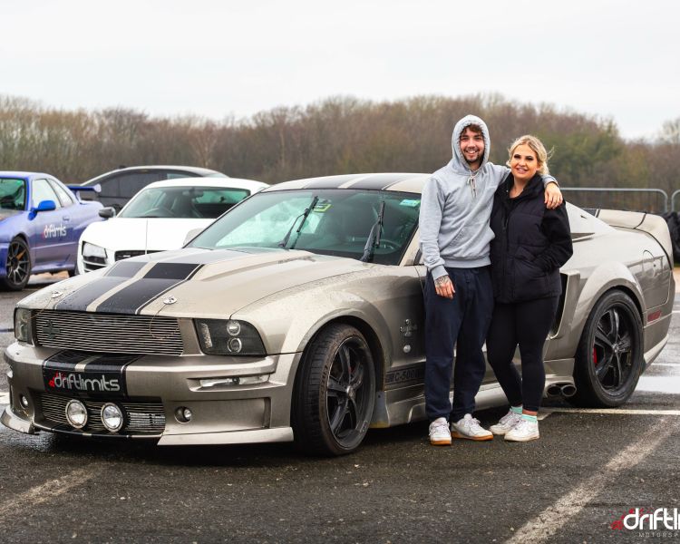 man and woman standing next to a sports car on a car photoshoot and passenger lap experience