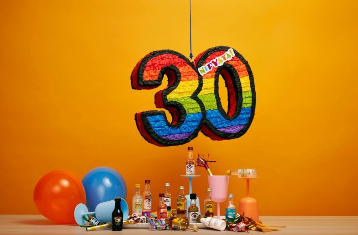 a pinata in the shape of the number thirty hanging over a selection of party drinks and balloons