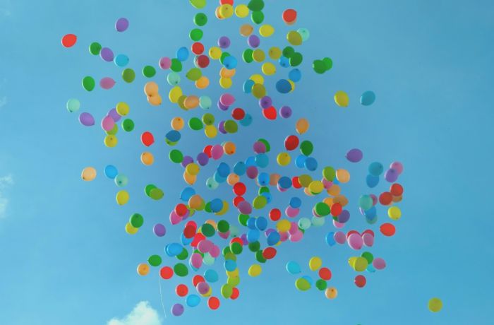 looking up at coloured balloons in a blue sky