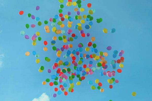 looking up at coloured balloons in a blue sky