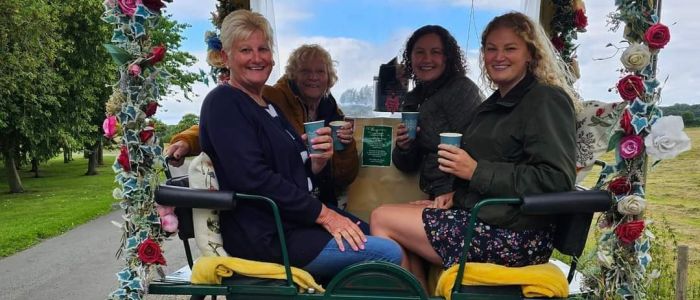 four ladies with takeaway drinks sitting in a carriage decorated with flowers on a horse carriage ride experience