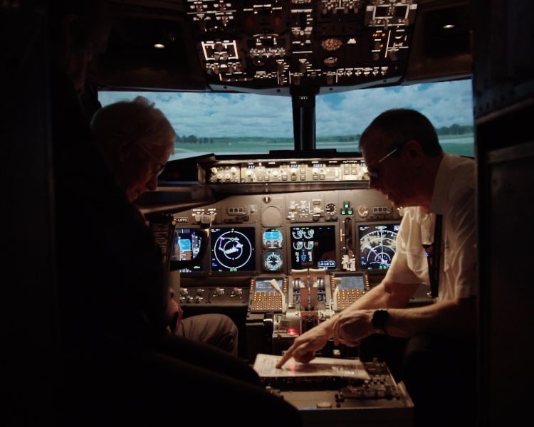 person being shown notes by a copilot in the cockpit of a plane flight simulator at deeside flight simulators