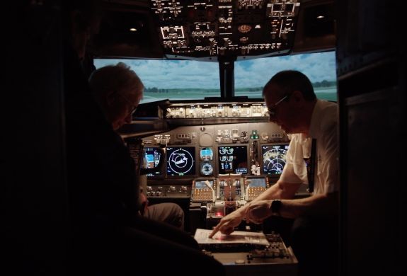 person being shown notes by a copilot in the cockpit of a plane flight simulator at deeside flight simulators