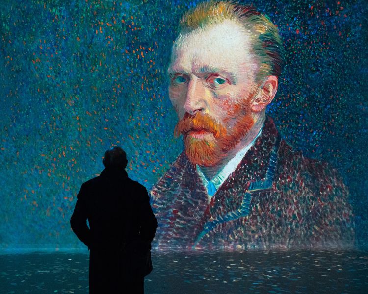 person looking at van gogh's self porait at the frameless immersive art exhibition in london