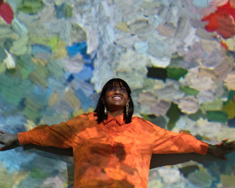 woman standing against a wall at the frameless immersive art exhibition in london