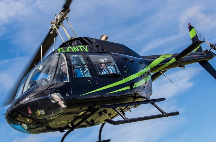 a black helicopter with green stripes in the air for a helicopter ride experience with adventure 001