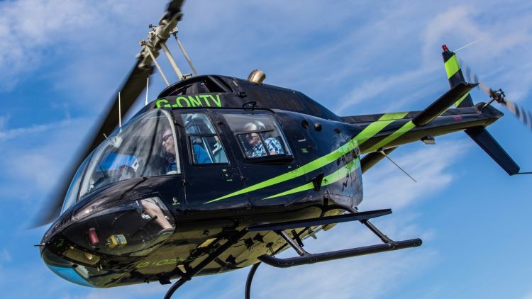 a black helicopter with green stripes in the air for a helicopter ride experience with adventure 001