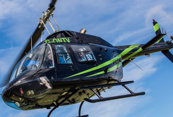 a black helicopter with green stripes in the air for a helicopter ride experience with adventure 001