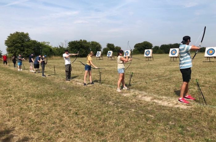 Row of people aiming at targets on archery experience
