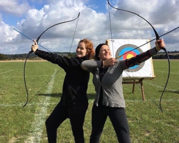 2 girls posing with bows for archery