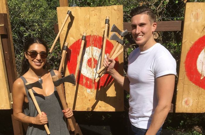man and woman posing with axes in front of targets on an axe throwing experience
