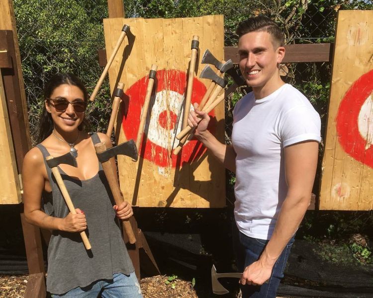 man and woman posing with axes in front of targets on an axe throwing experience