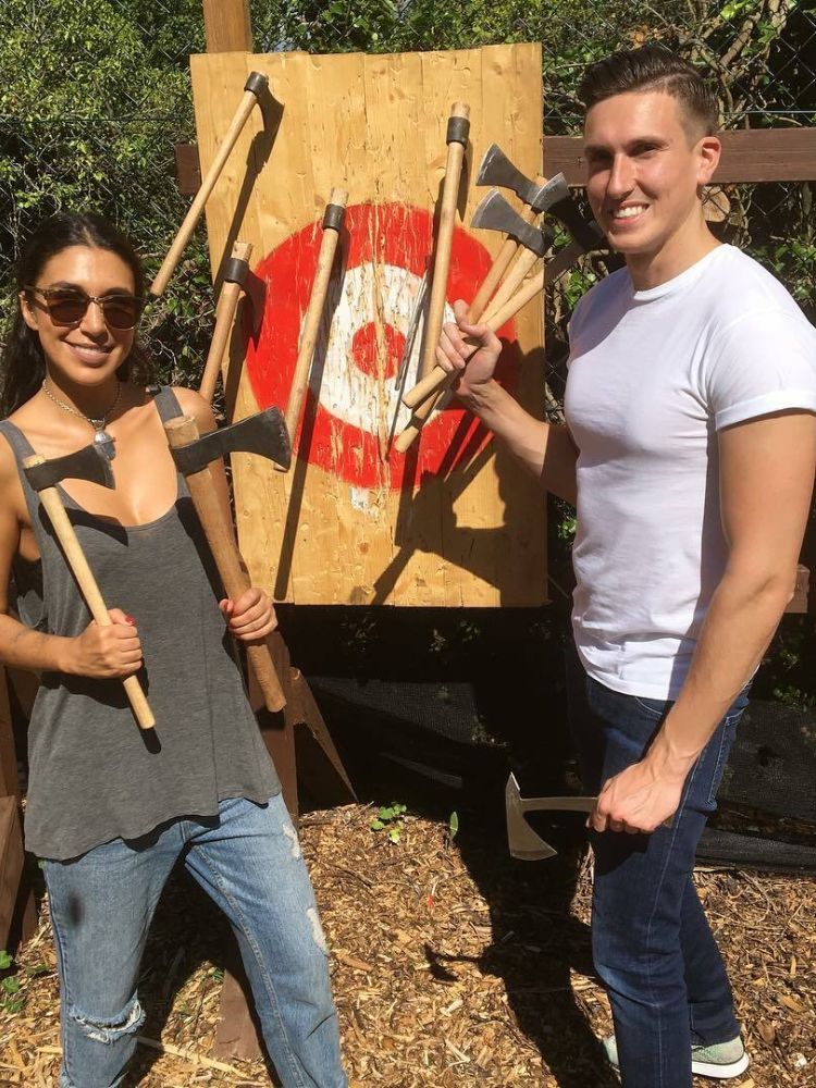 man and woman posing with axes in front of targets on an axe throwing experience