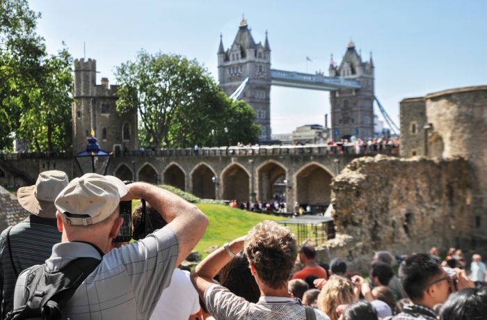 tourists taking photos of tower bridge from inside the grounds of the tower of london