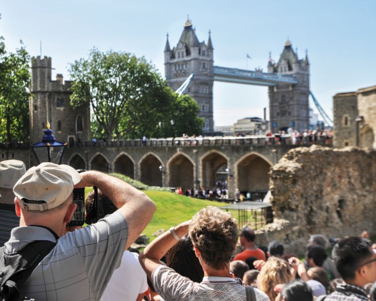 tourists taking photos of tower bridge from inside the grounds of the tower of london