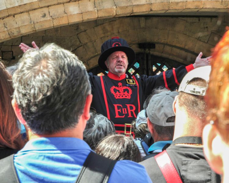 people listening to a guard talking at the tower of london