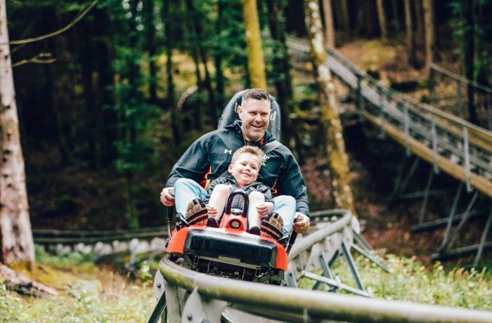 man and youngster on a fforest coaster ride experience through forest