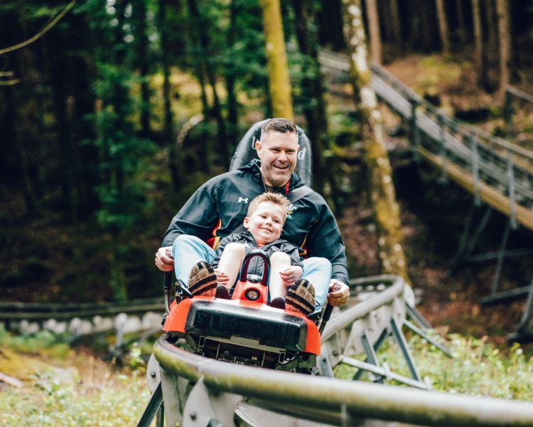 man and youngster on a fforest coaster ride experience through forest