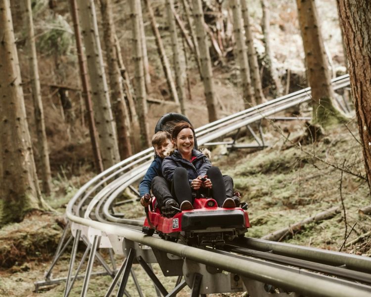 woman and youngster on a fforest coaster ride experience through forest