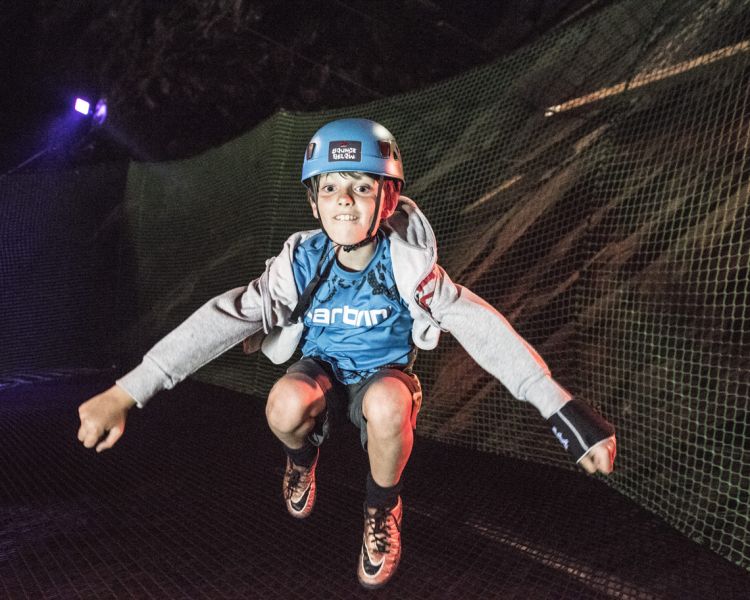young child bouncing on a trampoline inside a cave on a bounce below experience day