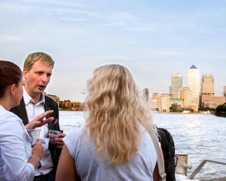 people on the banks of the river thames with view of the city of london behind them