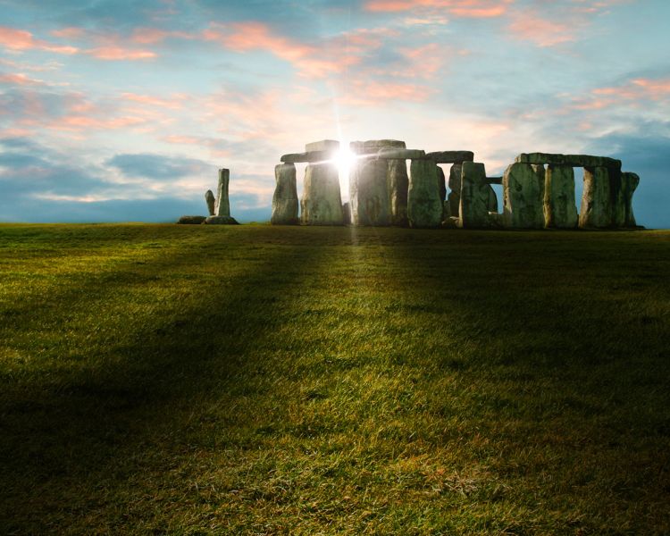 view of stonehenge with sunlight shining through the stones
