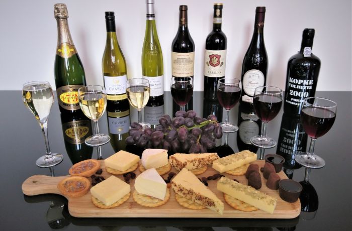 bottles of red wine and port lined up with a platter of cheese and crackers on a wine tasting experience with wine cottage