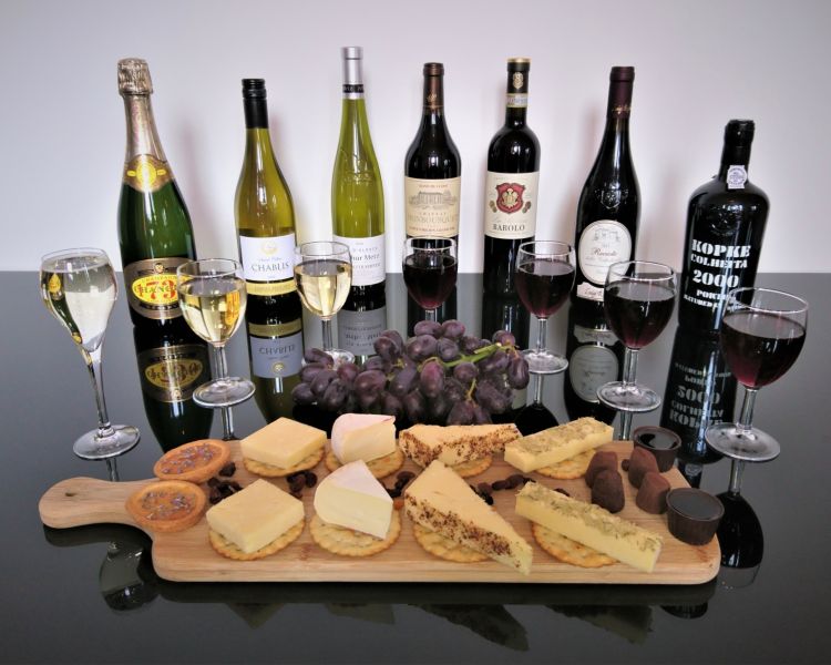 bottles of red wine and port lined up with a platter of cheese and crackers on a wine tasting experience with wine cottage