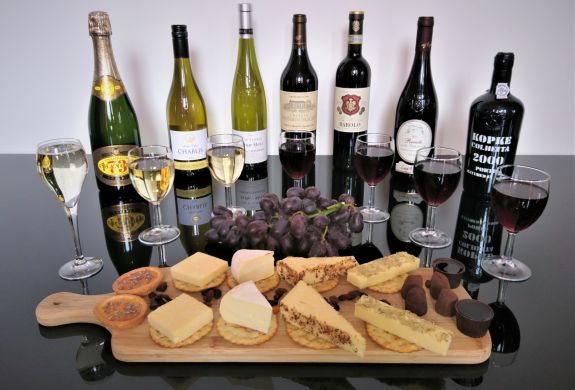 bottles of red wine and port lined up with a platter of cheese and crackers on a wine tasting experience with wine cottage
