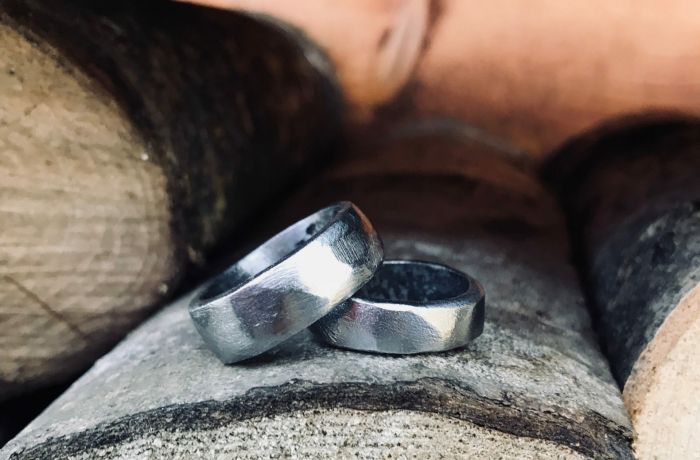 two wedding rings sitting on wooden logs
