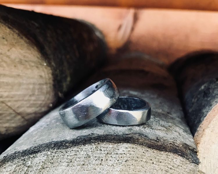 two wedding rings sitting on wooden logs