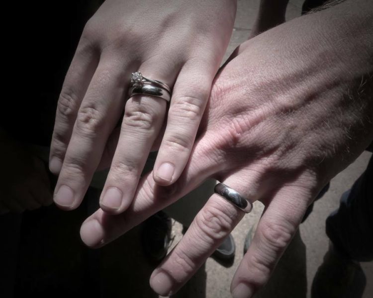 two hands wearing a silver wedding ring made on a ring making experience day