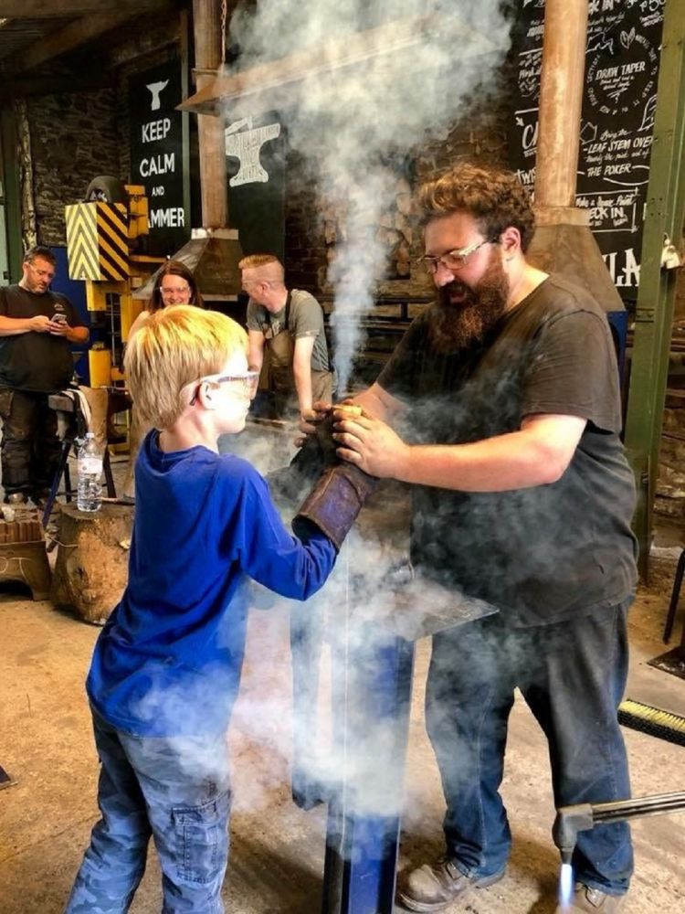 man and child in a forge on a sword making experience