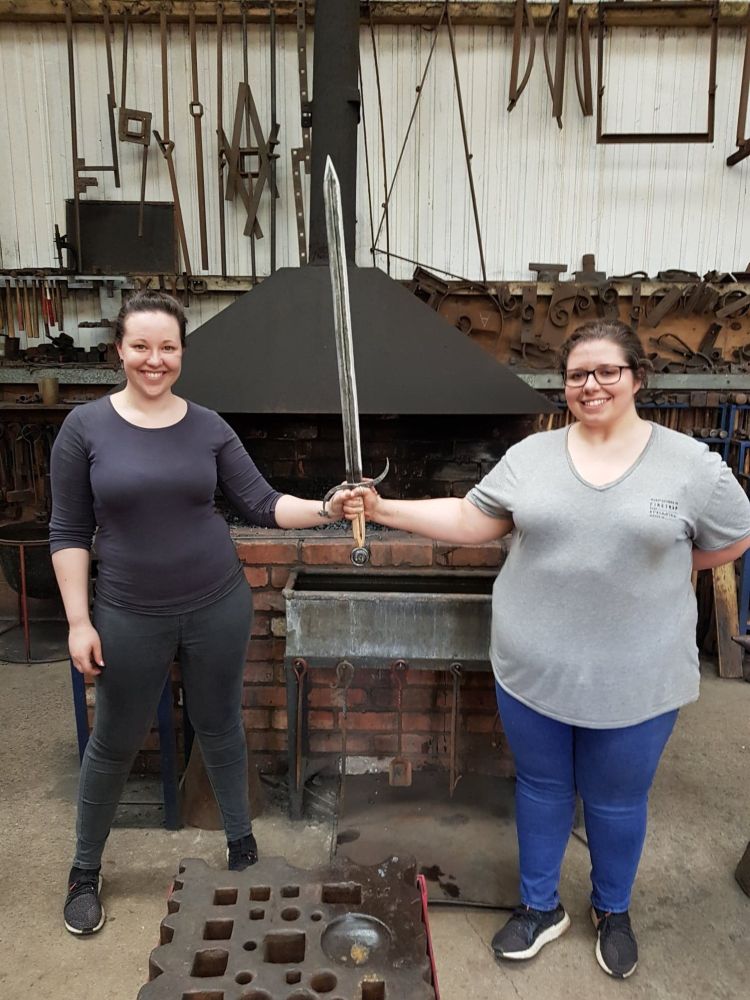 two ladies holding a sword made on a sword making experience