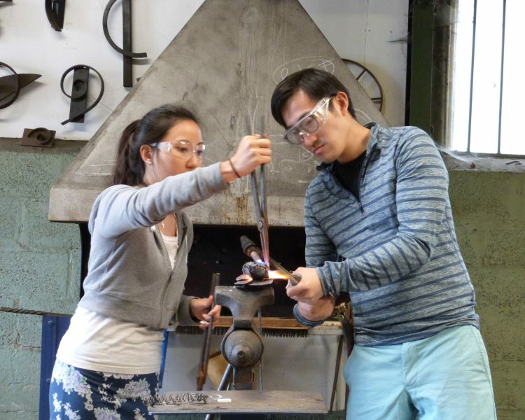man and woman in a forge on a couples blacksmith experience
