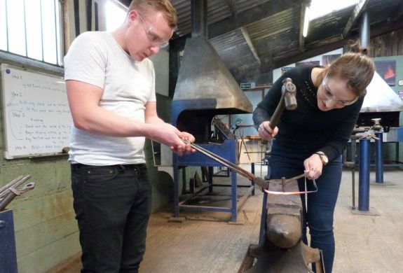 man and woman in a forge on a couples blacksmith experience