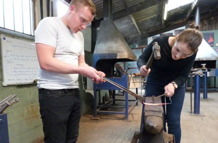 man and woman in a forge on a couples blacksmith experience