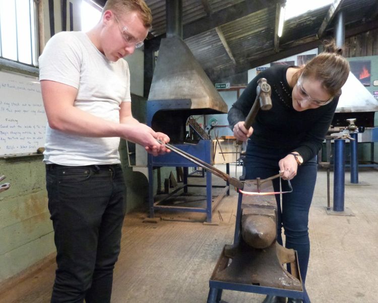 man and woman in a forge on a couples blacksmith experience