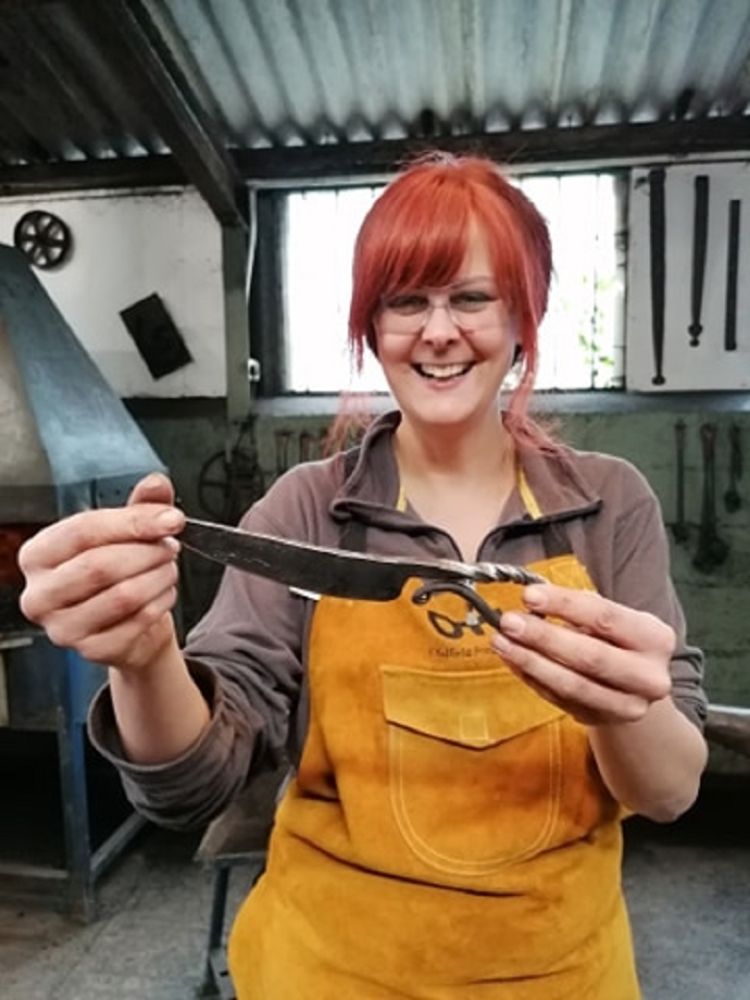 woman holding a knife she has made on a just for fun blacksmith experience