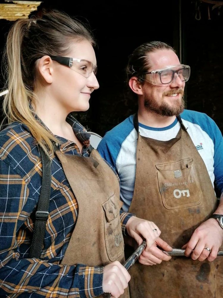 man and woman holding knives they have made on a just for fun blacksmith experience