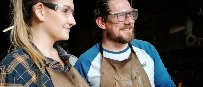 man and woman holding knives they have made on a just for fun blacksmith experience