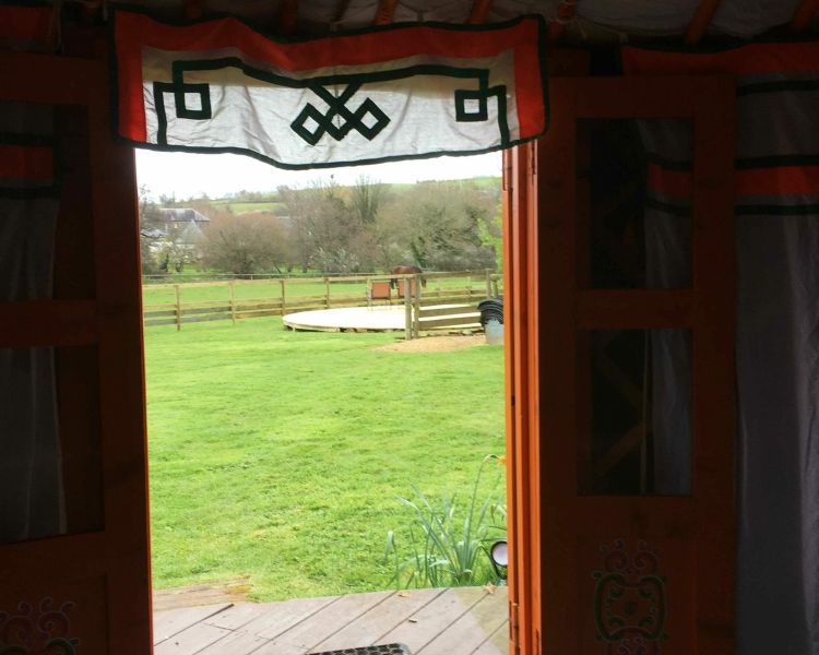 the view outside from the entrance of one of the devon yurts onto fields