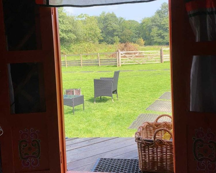 the view through the entrance of one of the devon yurts out onto fields
