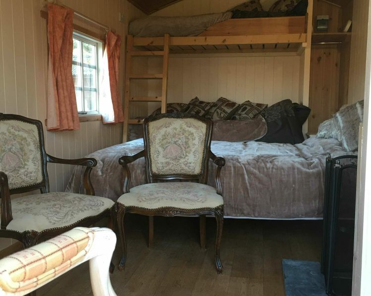 the inside of a shepherds hut set in the grounds of devon yurts showing the seating and sleeping areas
