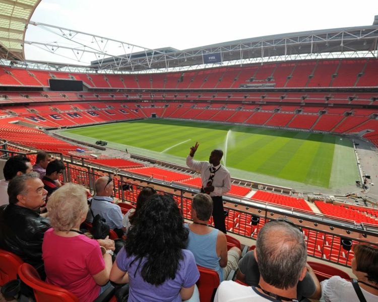 group sitting in stands listening to guide on a wembley stadium tour