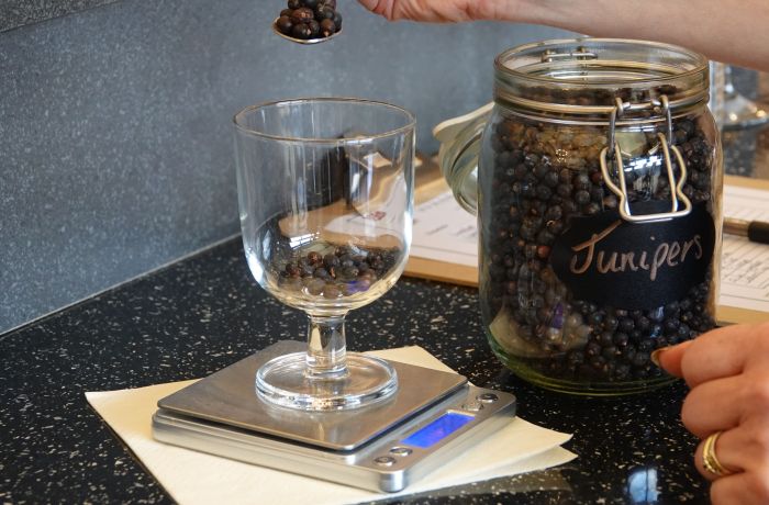 weighing juniper berries in a glass on a gin making experience in shropshire